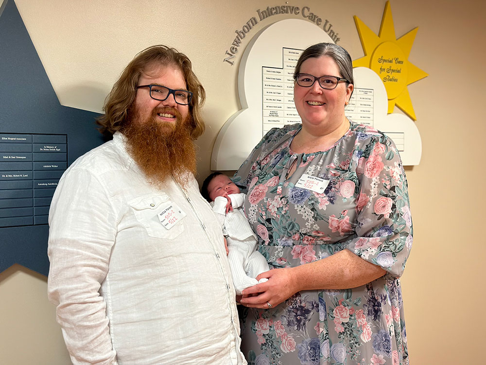 Kerrin Lucas and Charles Hayes holding their baby and smiling for camera