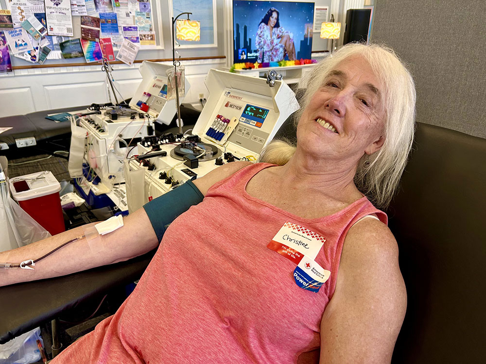 Christine Caulfield sitting in a blood donation chair and donating blood.