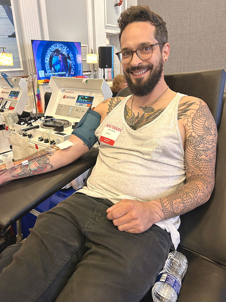 Greg Kirby sitting in a blood donation chair and donating blood.