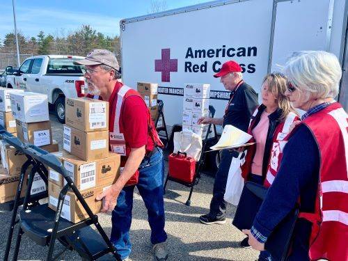four people carrying supplies from van