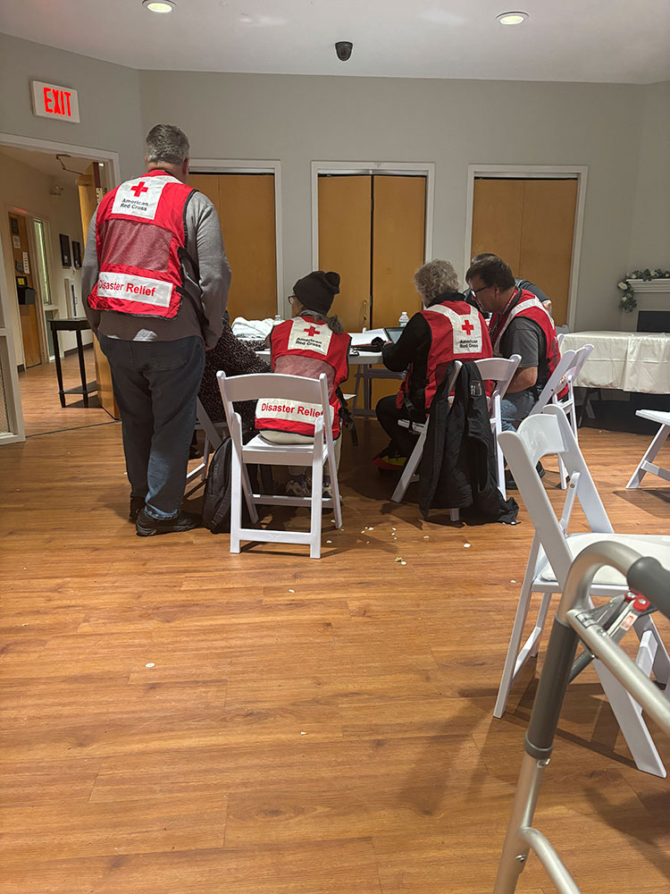 red cross volunteers and sitting at a table with paperwork spread out.