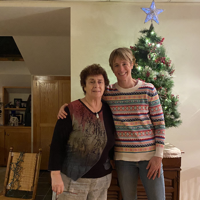An older woman stands next to her younger daughter.