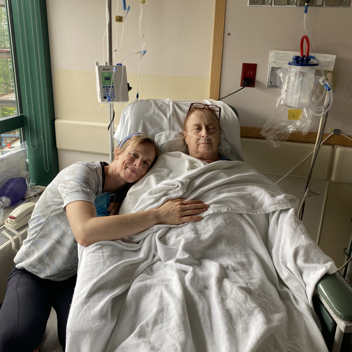 An older woman laying in a hospital bed while her younger daughter hugs her