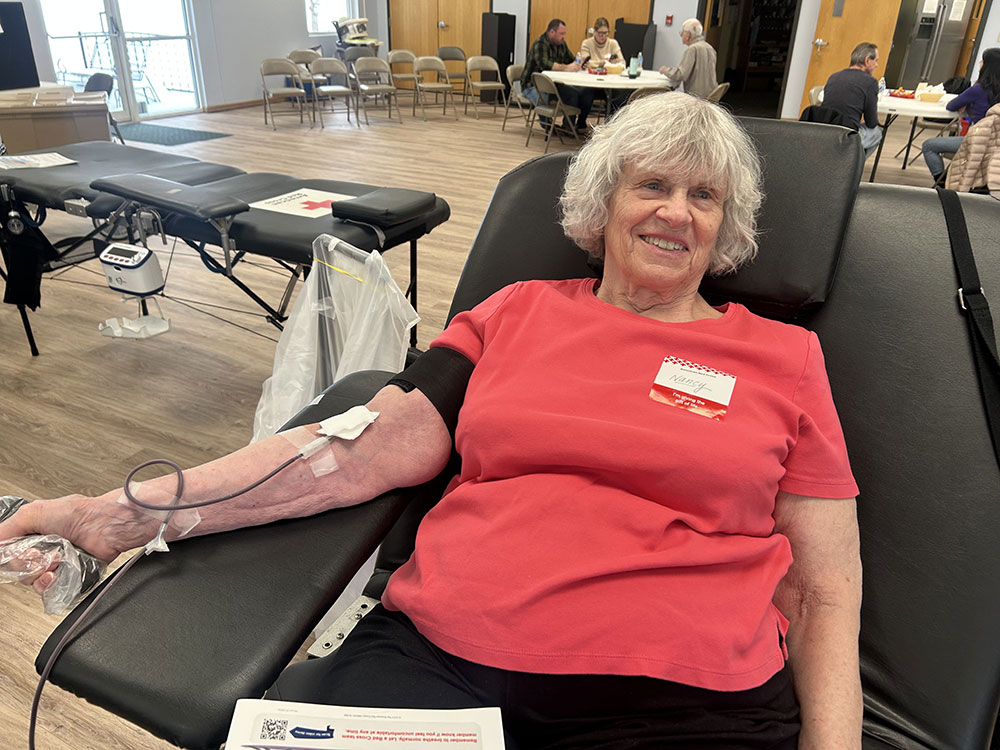 Nancy Schreyer sitting in a chair and donating blood.