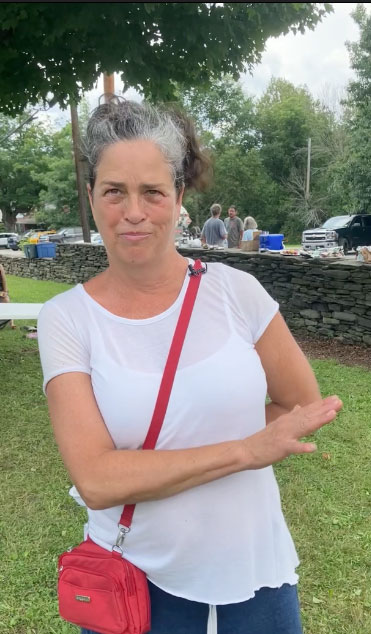 Paula Emery outside on grass with red handbag across shoulder.