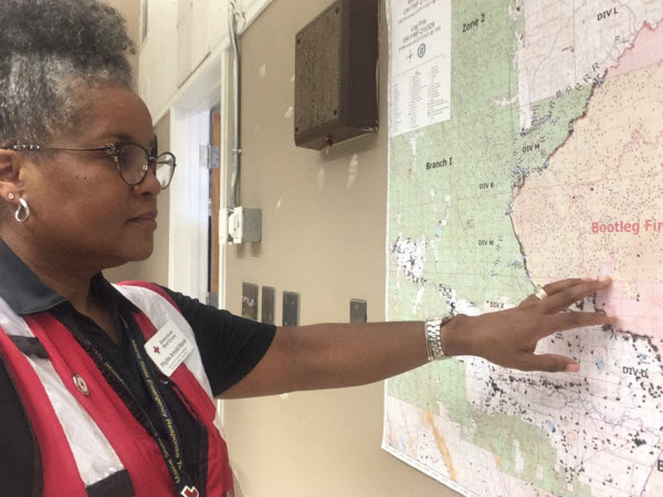 Phyllis wears a Red Cross volunteer vest and is looking at a map