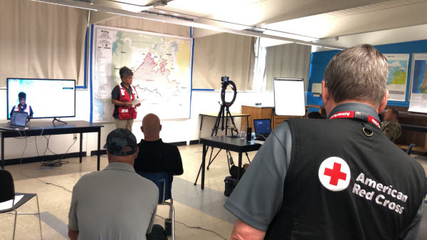 Phyllis is standing in front of a map giving a presentation