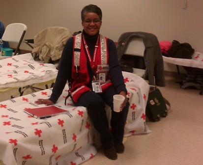 Phyllis sitting on a cot covered in a Red Cross blanket
