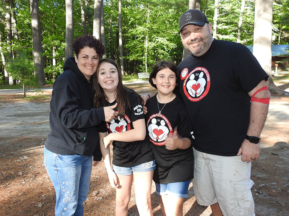 Poulin family group shot. Parents and two kids at camp grounds.