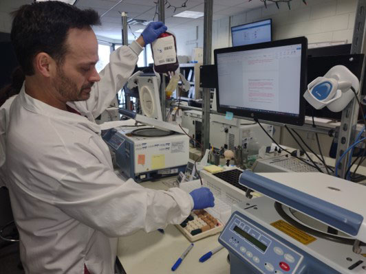 Ray Bissonnette in a lab and holding a blood bag.