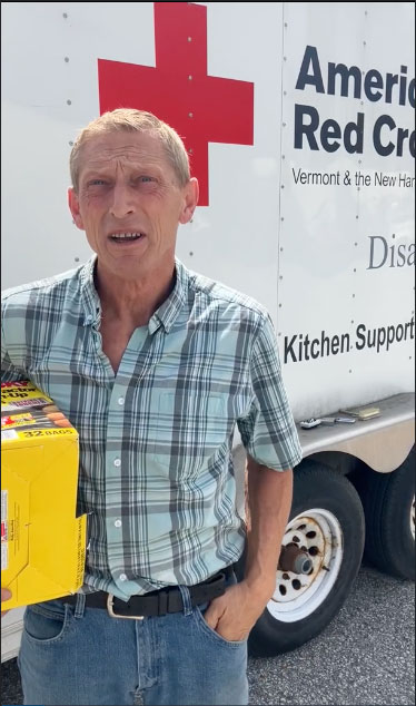 Russel Masi holding box and next to an American Red Cross vehicle.