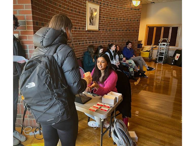 Sivani Arvapalli sitting at table handing out name tags.