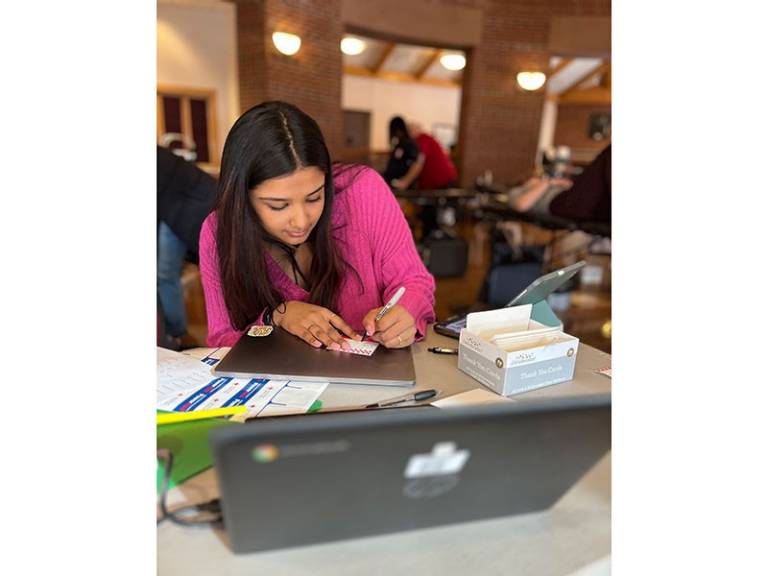 Sivani Arvapalli sitting at table filling out name tag.