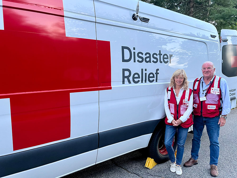 Red Cross volunteers Tony and Susan Mellon standing next to a Red Cross vehicle.