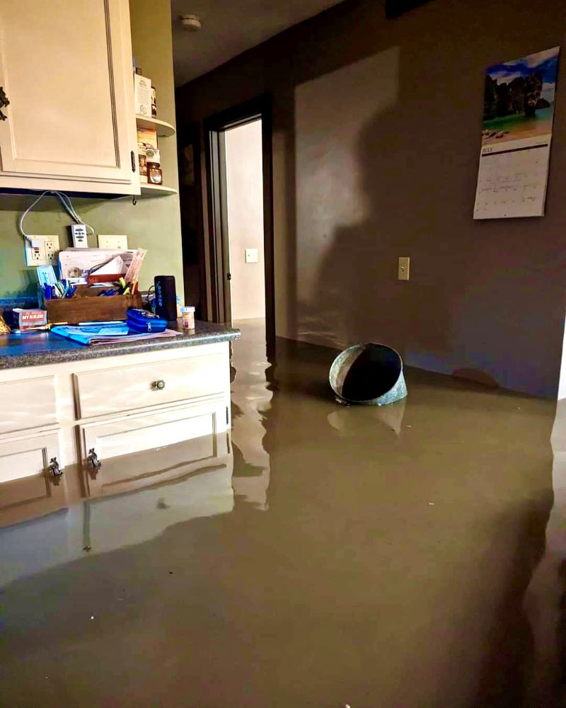 A bucket on the floor of a flooded kitchen