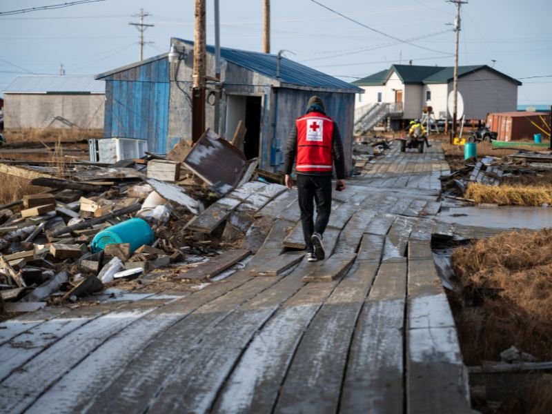 red crosser walking through damaged area.
