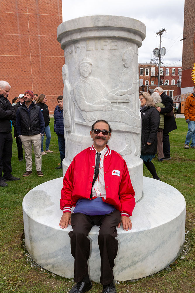 person sitting on sculpture that has a bench like seat.