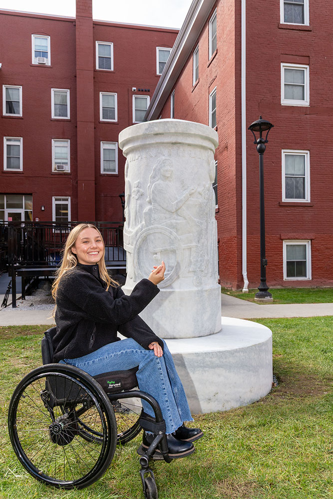 person in wheelchair smiling while next to sculpture.