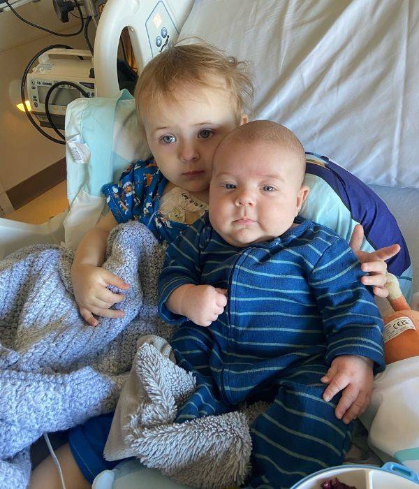 charlotte smiling in hospital bed with little sibling