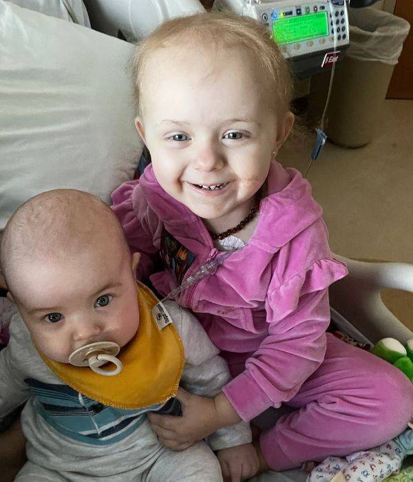 charlotte smiling in hospital bed with little sibling