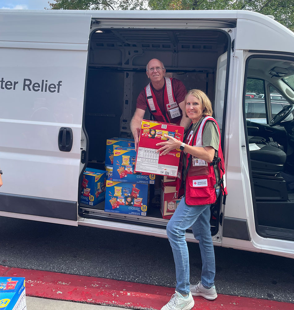 Red Cross volunteers Jeff and Laura Mann unloading boxes of food from a Red Cross van.