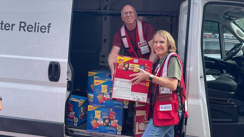 Red Cross volunteers Jeff and Laura Mann unloading boxes of food from a Red Cross van.
