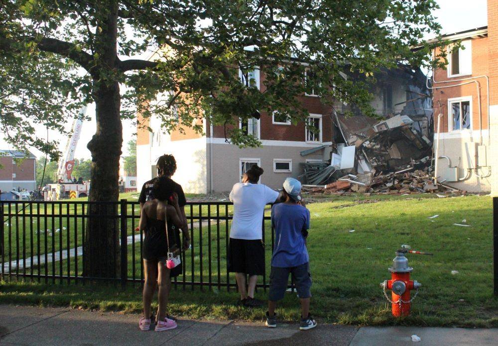 Four people looking at a destroyed home