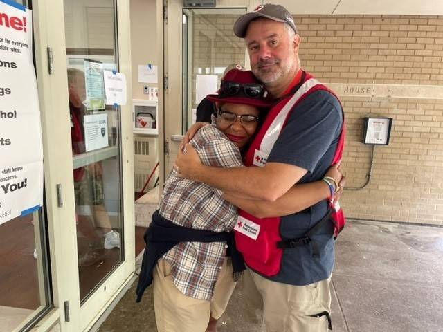 Red Cross worker hugs shelter resident