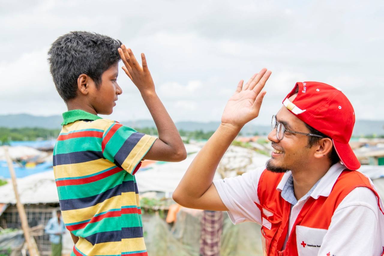 A young boy and a Red Cross volunteer give each other a high five