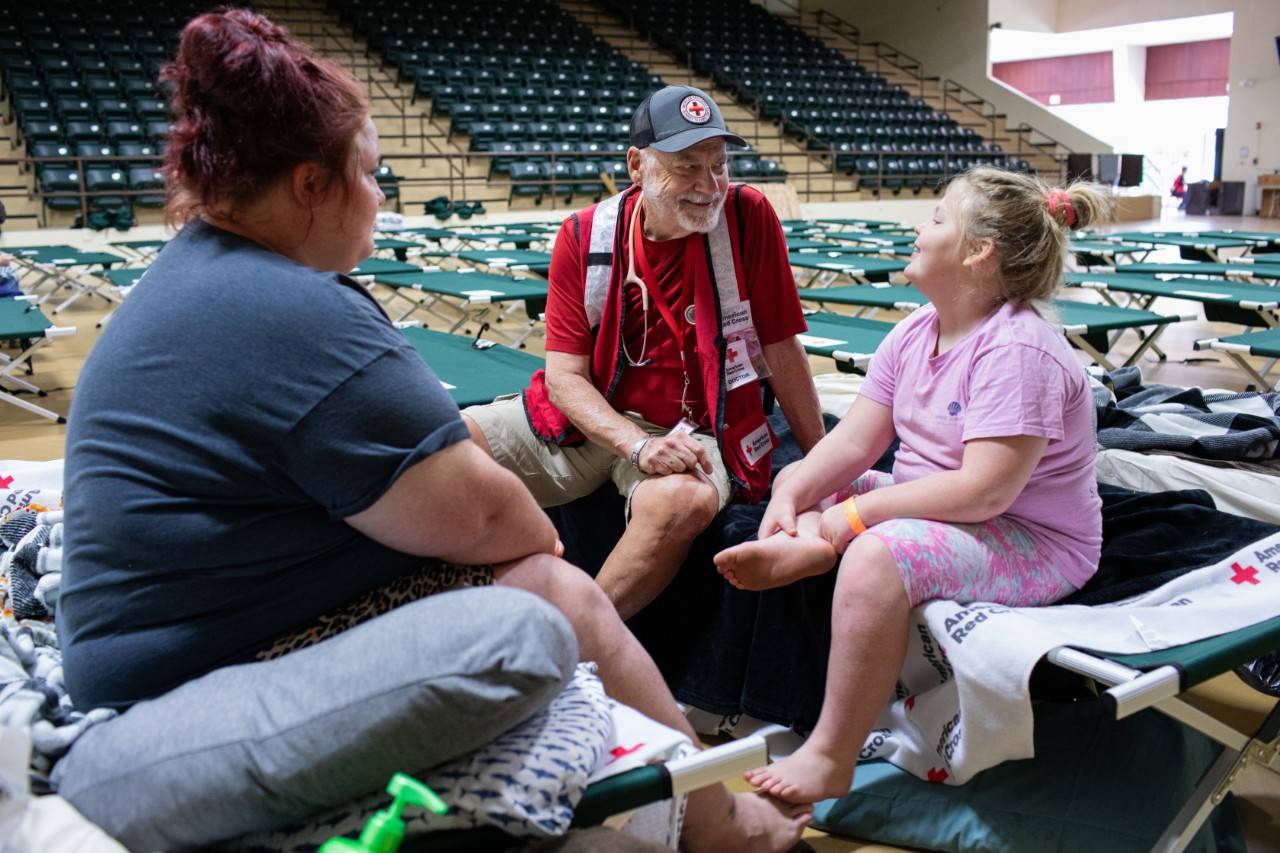 September 29, 2024. Perry, Florida.
Dr. Thomas Barela, an American Red Cross disaster health services volunteer from Seattle, visits with Amber and her family at the Red Cross shelter in Perry, Florida, after Hurricane Helene devasted the family s home. 
 I can t really know what it s like to be in their situation,  he said,  but I can be here for them. I just try to be as supportive as I can to help them cope. 
Amber and her family found refuge at the American Red Cross emergency shelter in Perry, Florida, after Hurricane Helene devastated their home. They spent the night of the hurricane at a county evacuation shelter and couldn t believe the destruction when they returned home the next morning.
 We pulled into the driveway, and my daughter began to cry   she said,  Mom, we don t have a home anymore.  
Having survived three hurricanes in the past fifteen months, Amber s first call was to 1-800-REDCROSS to find the nearest shelter.
 As soon as I pulled up to the shelter,  Amber said,  it made me feel good. I thought to myself, this is safe, and I m going to be OK. 
Amber said,  The Red Cross people here at the shelter have been really kind to me. They ve given us everything we need, they ve played with my kids, and they ve treated us so well. I m just really grateful to have a place like this right now when we need it. 
Photo by Marko Kokic/American Red Cross