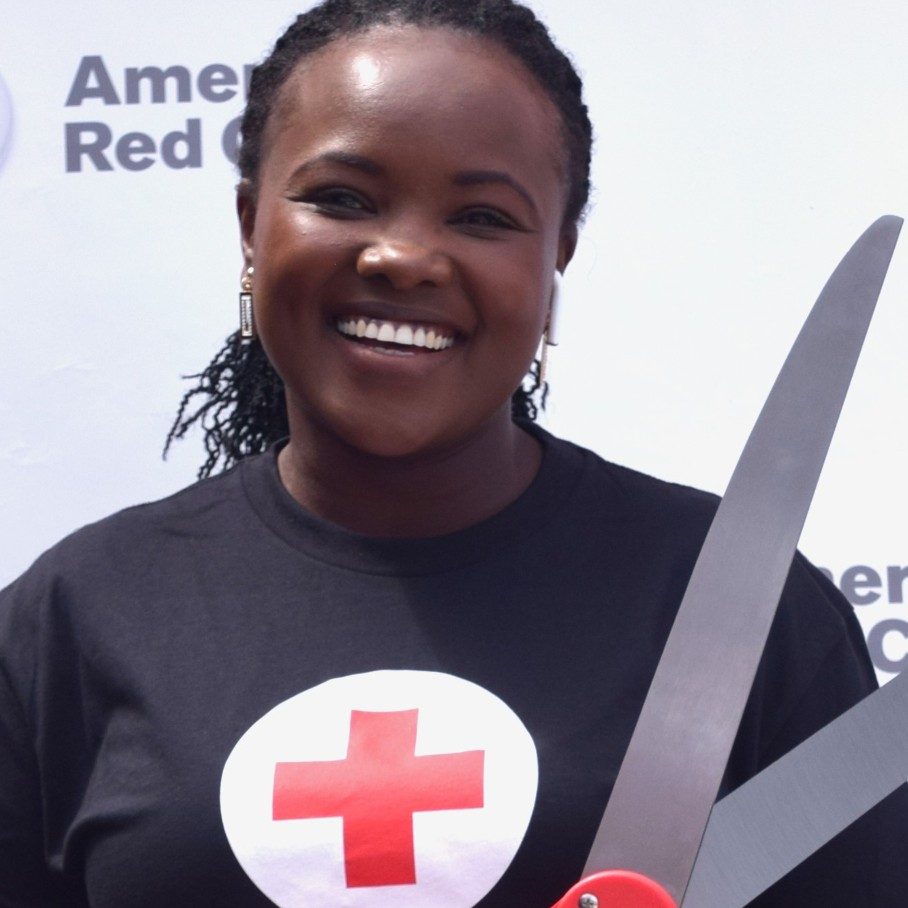 woman smiling with giant ribbon-cutting scissors
