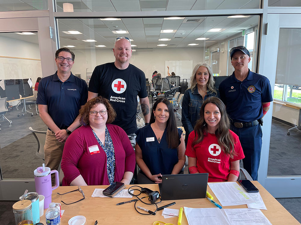 Group photo of blood drive workers and volunteers behind a desk.