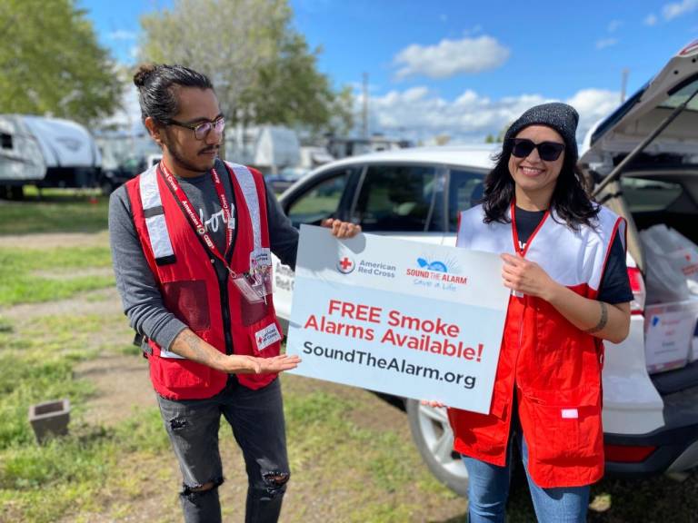 juan with volunteer holding free smoke alarm signage