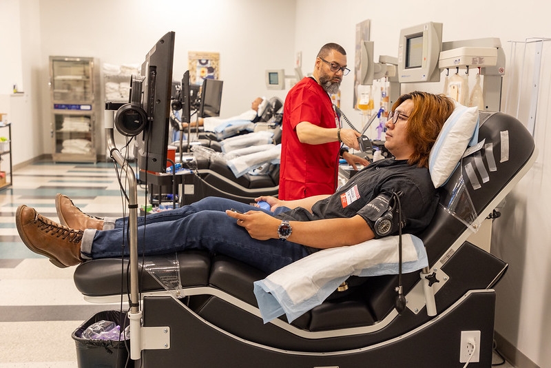 person sitting in chair next to a Red Cross nurse, ready to donate blood.