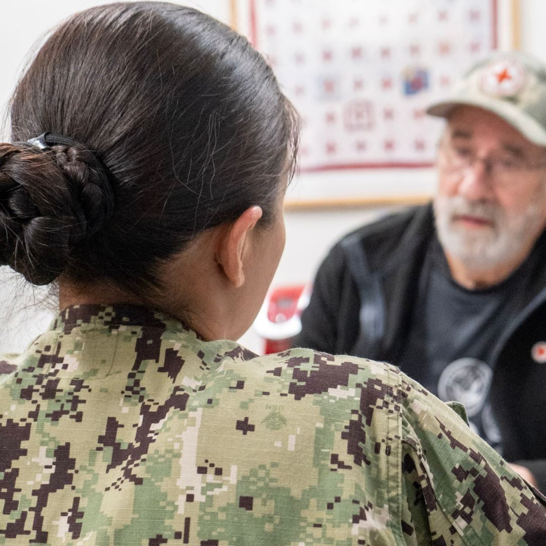 red cross volunteer talking to woman in the military