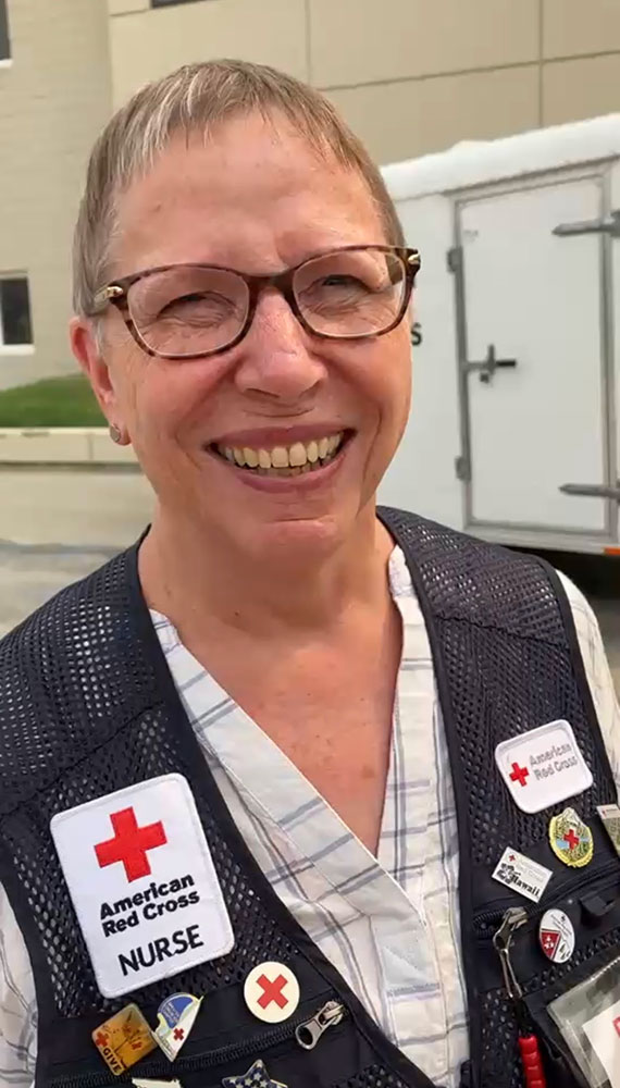 Barb Wharton wearing glasses and Red Cross vest smiles for picture.