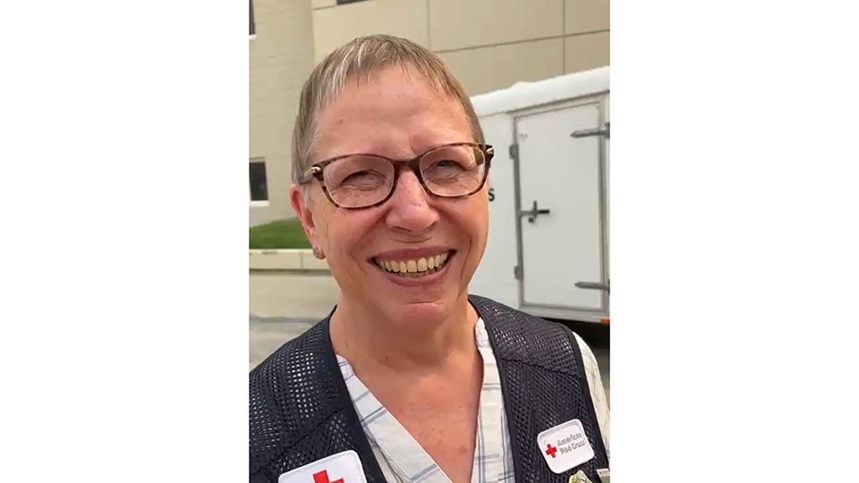 Barb Wharton wearing glasses and Red Cross vest smiles for picture.
