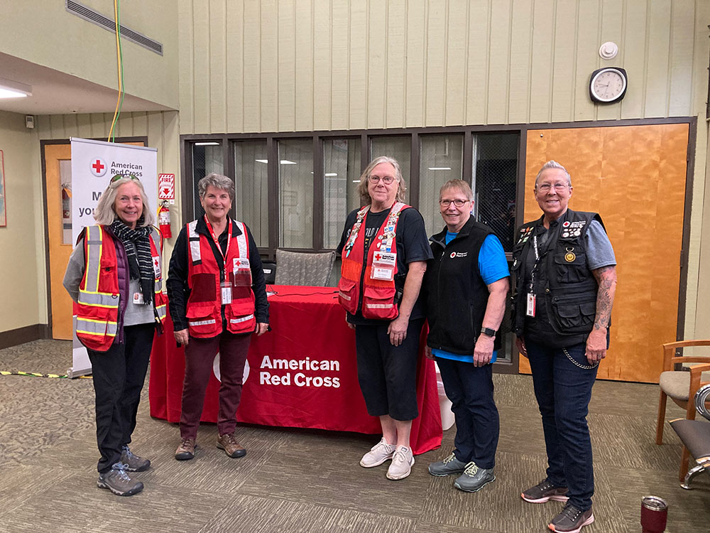 Barb Wharton and four other Red Cross volunteers in vests smile for group picture.