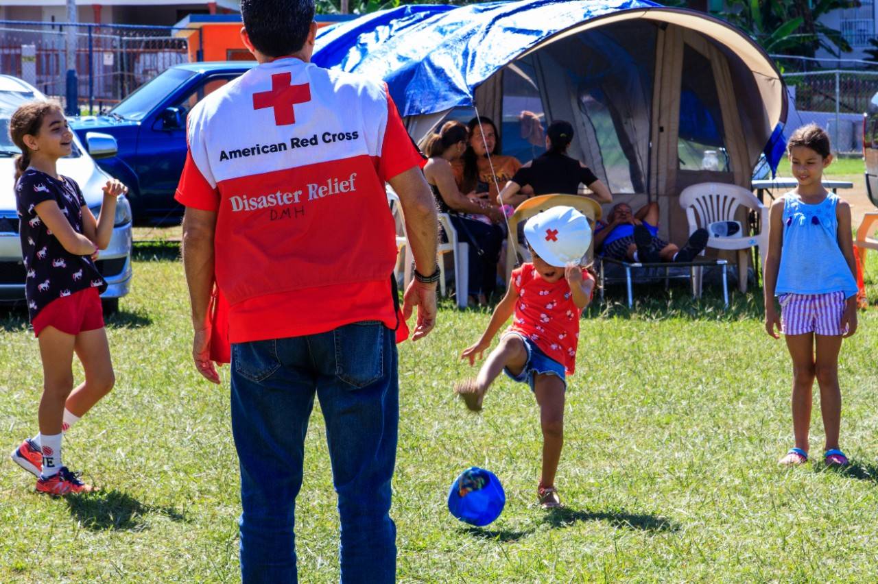 A young boy and a Red Cross volunteer give each other a high five