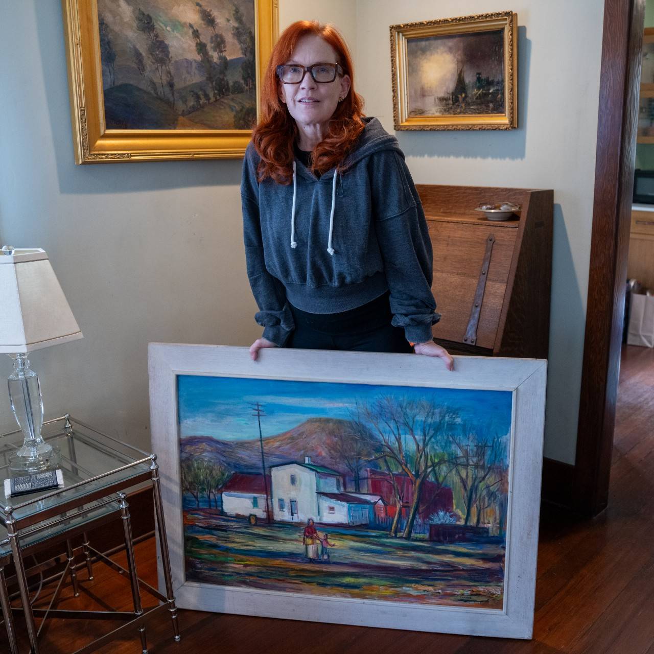Volunteer DeAnne Todd with a painting she rescued from her home that was destroyed by wildfires