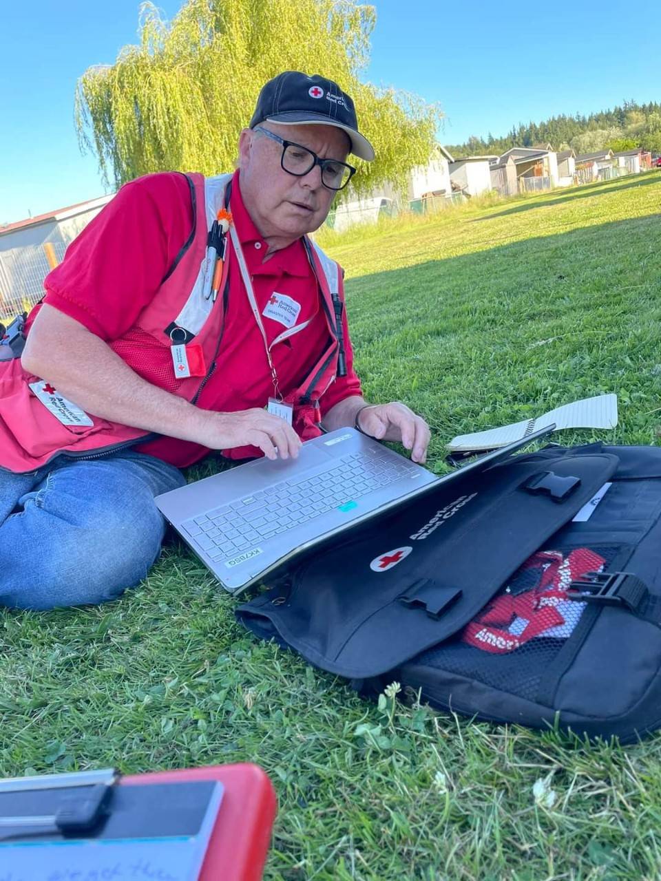 david allen in grass viewing laptop with red cross case