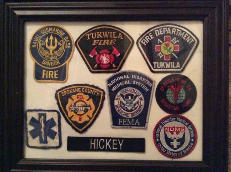 A framed collection of badges representing the various agencies Matt has worked for.