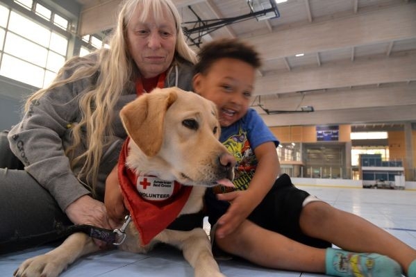 woman and young child embracing therapy dog