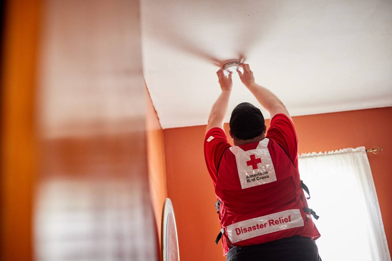 May 14, 2022. Central Falls, Rhode Island. Red Cross volunteer Brian Butterworth installs free smoke alarms during a Sound the Alarm event in Central Falls, Rhode Island. Over the course of the day, he installed 18 alarms. Butterworth knows first-hand the importance of fire safety because of his work with the local Red Cross Disaster Action Team to support people displaced by home fires. “As a member of the disaster action team, I witness the aftermath of home fires and the impact they have on residents,” he said. “Sound the Alarm and the year-round Home Fire Campaign provide an opportunity to meet with families before tragedy strikes, providing tips that may help prevent a fire before it starts and installing smoke alarms that will alert residents in the event of a fire. This work has the potential to save lives and has been extremely rewarding.” Photo by Jaka Vinšek/American Red Cross
