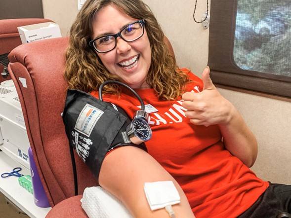 A girl gives a thumbs up while donating blood