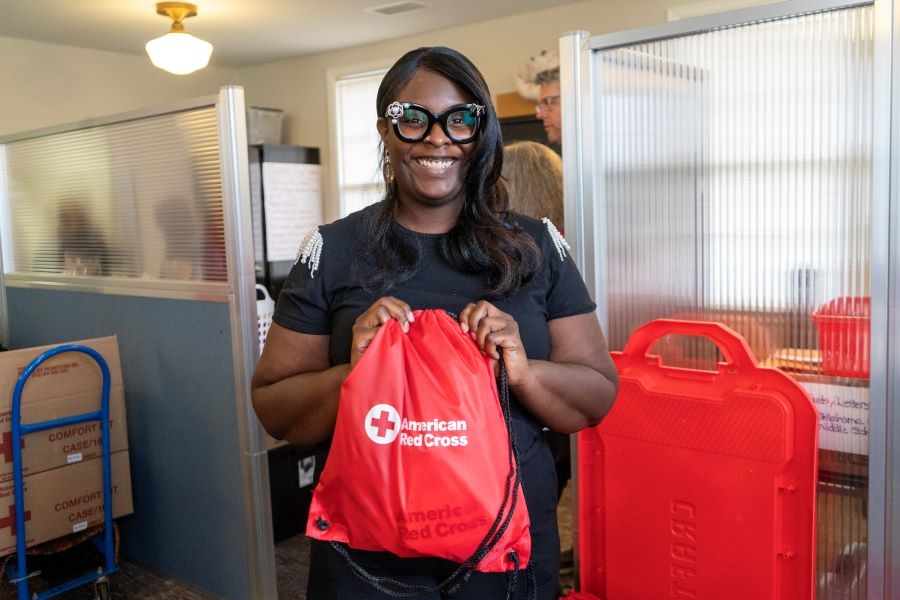 Leah Sumpter wearing glasses and holding an American Red Cross bag in an office.