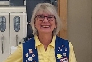 Nancy stands wearing vest with Red Cross pins
