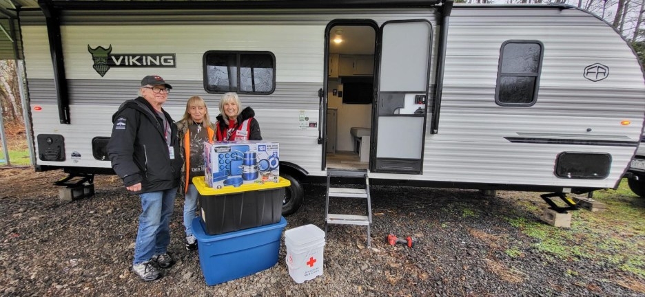 residents and red cross volunteer standing in front of RV
