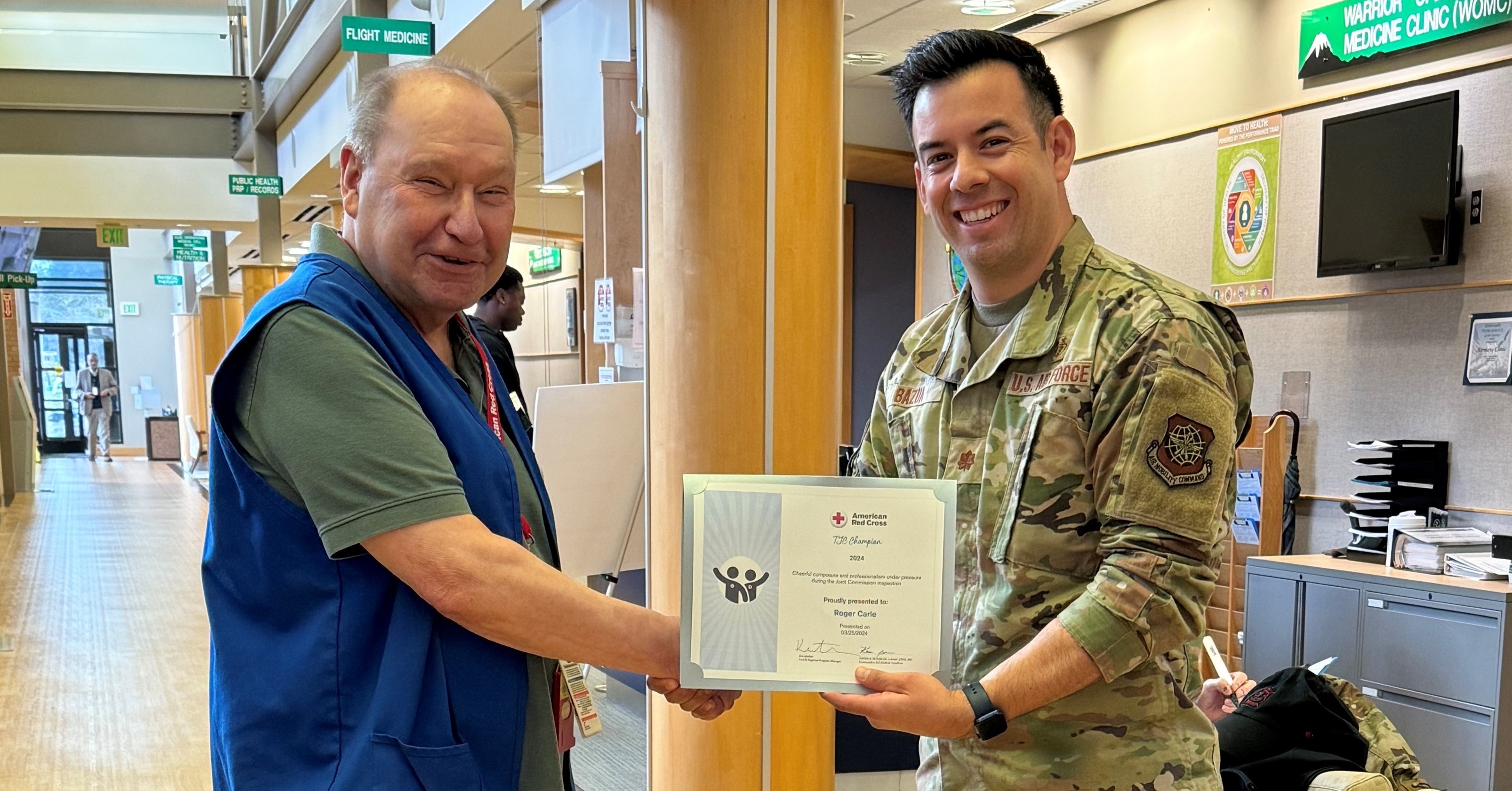service member in uniform shaking red cross volunteers hand