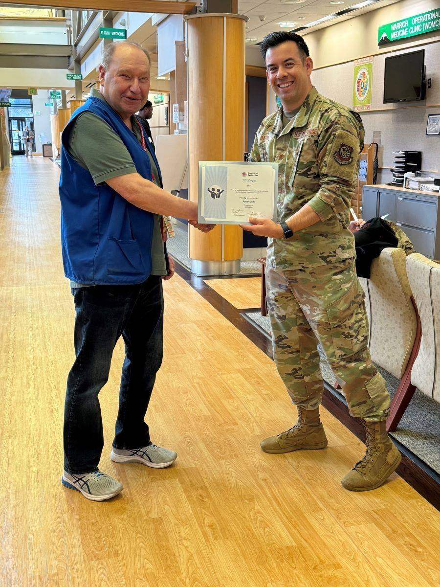 service member in uniform shaking red cross volunteers hand